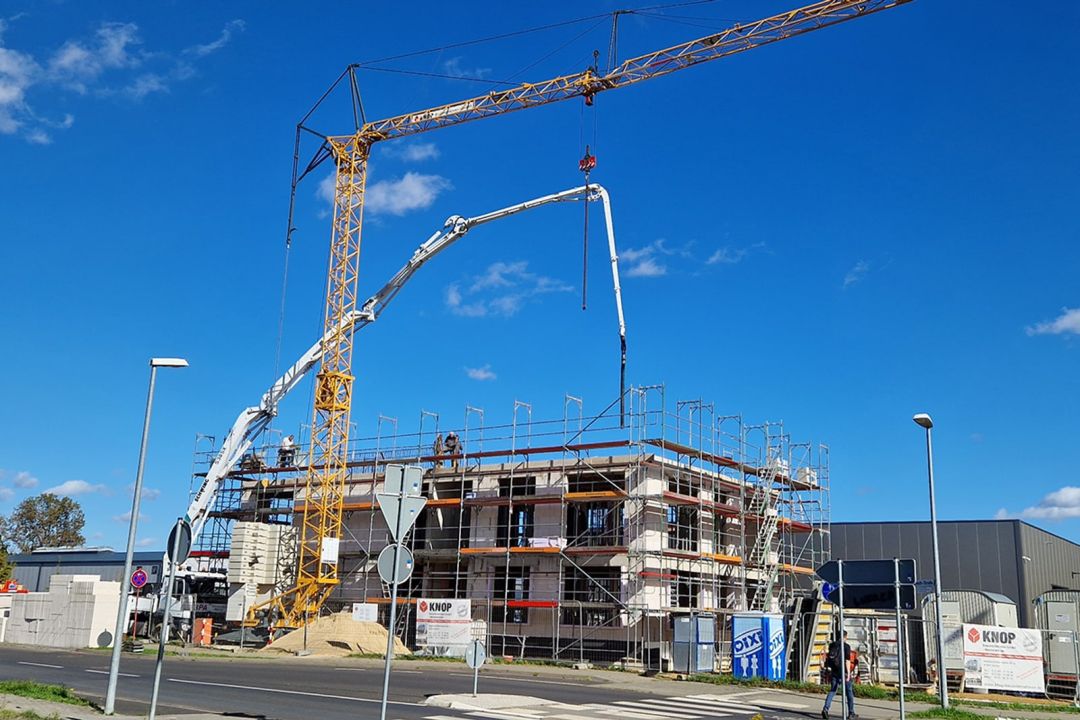 Rohbau eines mehrgeschossigen Gebäudes mit Kran und Betonpumpe auf einer Baustelle von KNOP
