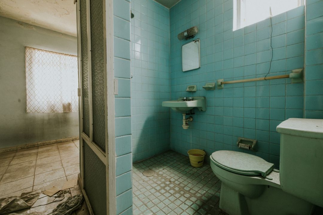 Älteres Badezimmer mit grünen Wandfliesen und alten Sanitärobjekten